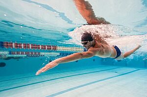 Unter Wasseraufnahme eines schwimmenden Menschen mit Badekappe und Schwimmbrille der kraftvolle Kraulzüge macht.