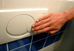 Eine Hand drückt die Wasserspartaste an einer Toilettenspülung.