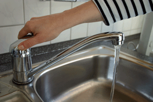 Eine Hand bedient den Einhebelmischer einer Garnitur auf einem Küchenwaschbecken