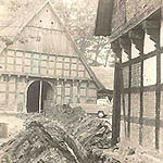 Historisches schwarz-weißfoto eines Vierständer-Fachwerkhauses, davor ein VW Pritschenwagen