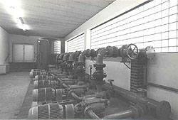 Blick in eine Halle eines Wasserwerkes mit mehreren Pumpen und Stellrädern.